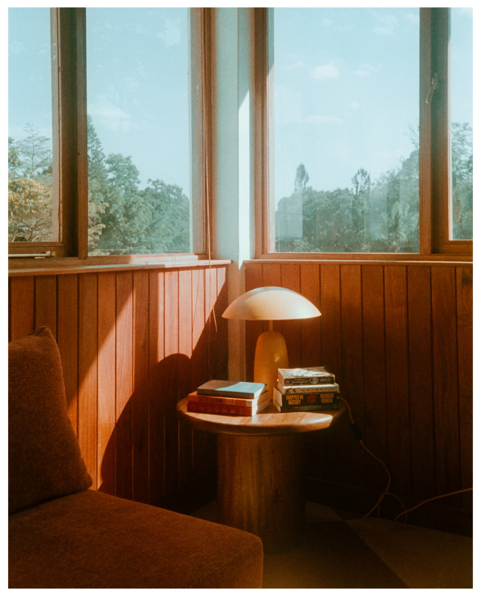 Wood panelled lounge nook with side table, books and windows, shot on film